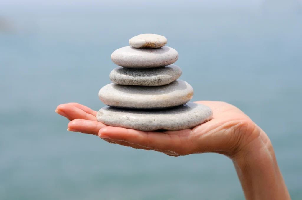 hand holding a stack of rocks for drop the rock therapy technique