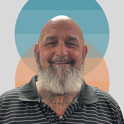 Person with a beard wearing a striped shirt and smiling.
