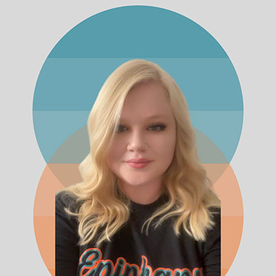 Person with long blonde hair wearing a black shirt with orange text.