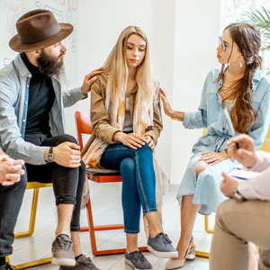 People sitting in a support group, comforting each other.