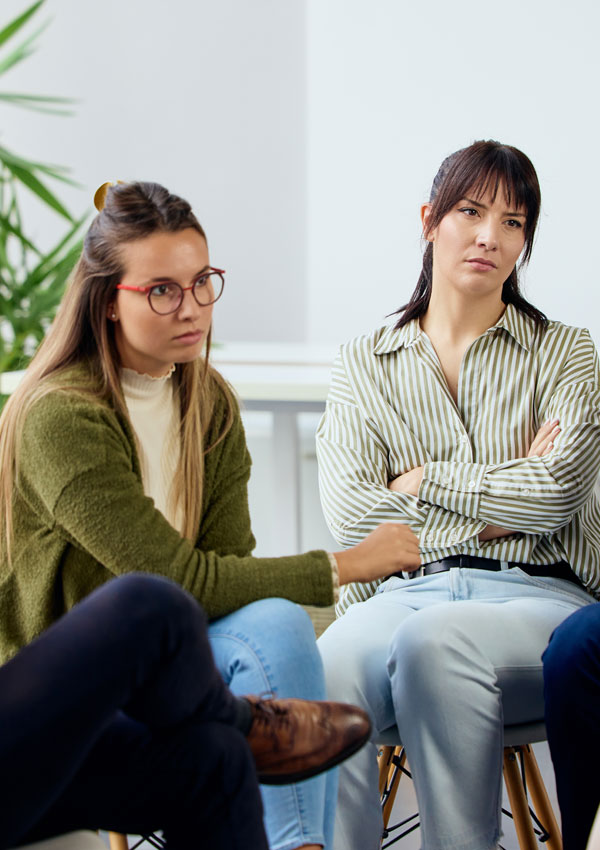 Person wearing striped shirt sitting with crossed arms.